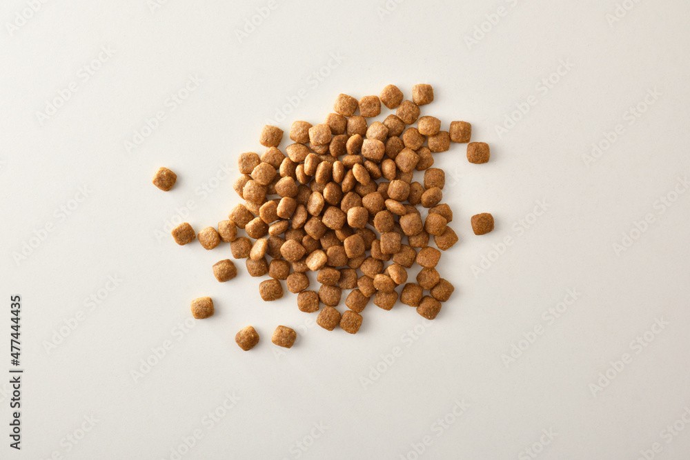Pile of dry food kibbles for pets on white top Pile of dry food kibbles for pets on white top