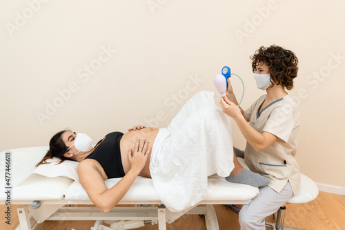 Gynecologist holding a pelvic floor muscle exercise device to prepare for the giving of birth of a woman lying photo