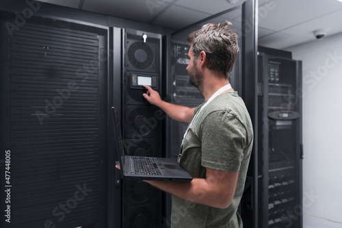Schilderij op canvas Data Center Engineer Using Laptop Computer Server Room Specialist Facility with Male System Administrator Working with Data Protection Network for Cyber Security or Cryptocurrency Mining Farm