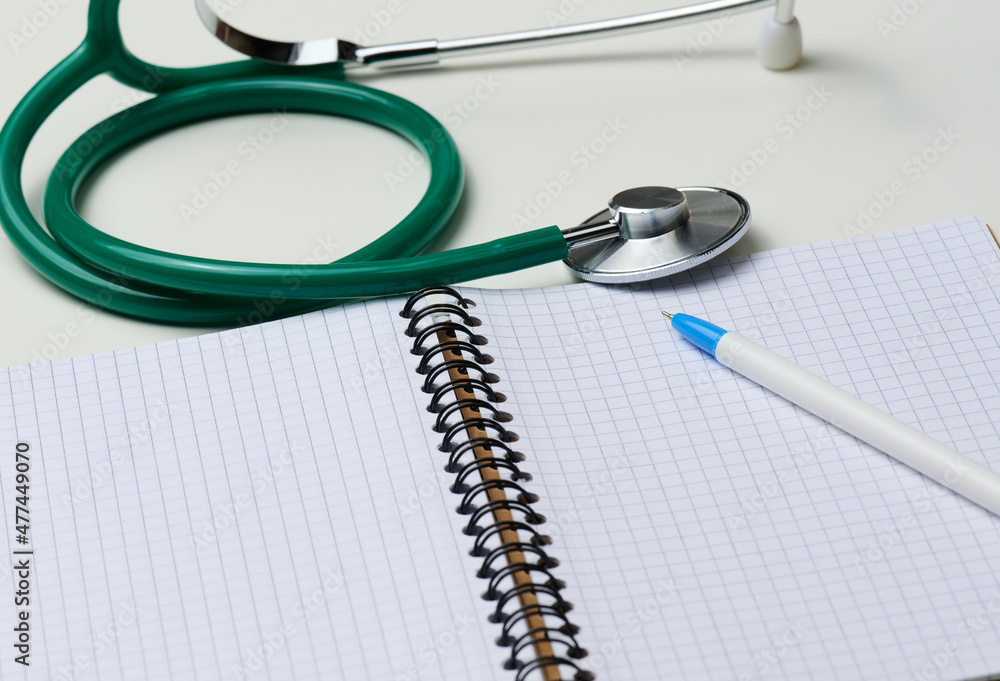 open blank notebook with pen and stethoscope, white table open blank notebook with pen and stethoscope, white table