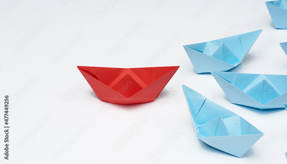 group of paper boats on a white background. concept of a strong leader in a team, manipulation of the masses, following new perspectives, collaboration and unification. Startup group of paper boats on a white background. concept of a strong leader in a team, manipulation of the masses, following new perspectives, collaboration and unification. Startup