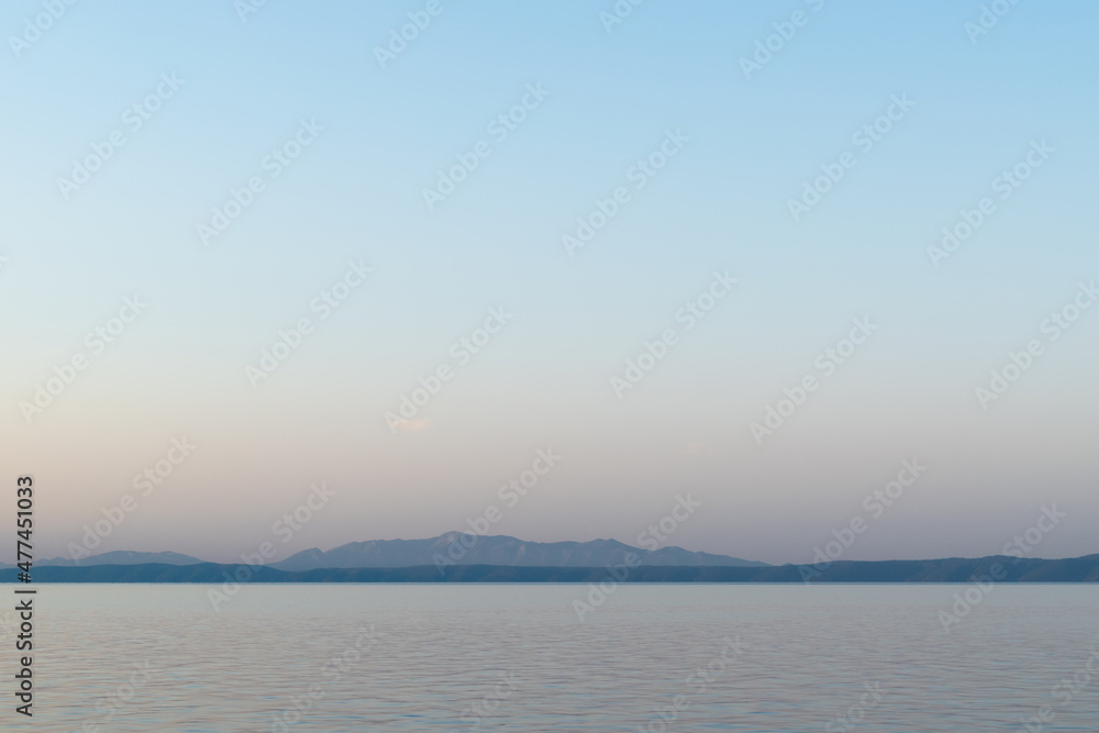 Hazy silhouettes of islands Brac and Hvar across Adriatic sea during summer morning captured from Croatia coast