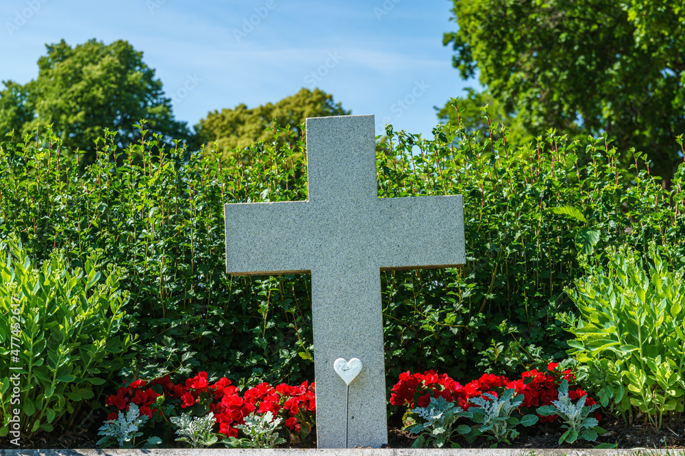 Grave with a large white cross surrounded by flowers