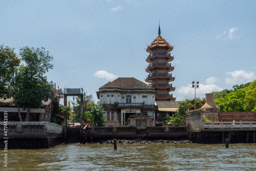 House on the banks of the Chao Phraya River with the Che Chin Khor Temple Pagoda in the background, - Bangkok, Thailand. House on the banks of the Chao Phraya River with the Che Chin Khor Temple Pagoda in the background, - Bangkok, Thailand.