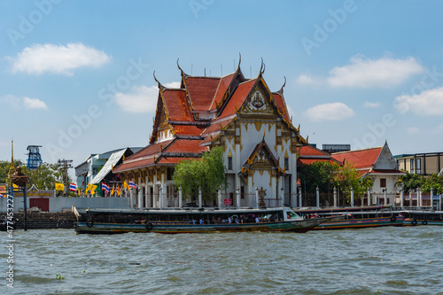 Boat on the Chao Phraya River in front of the Buddhist temple Wat Rakhangkhositaram, Bangkok, Thailand.