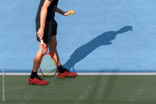 Tennis player with the ball in hand is ready to serve at start of game. Young male athlete play tennis on blue hard court. Sports background with copy space photo