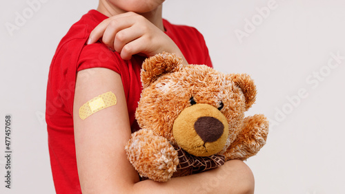 Children in red t-shirt holds toy and shows his shoulder after vaccination.