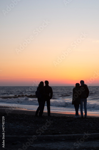 two couples in love embrace at sunset by the sea.