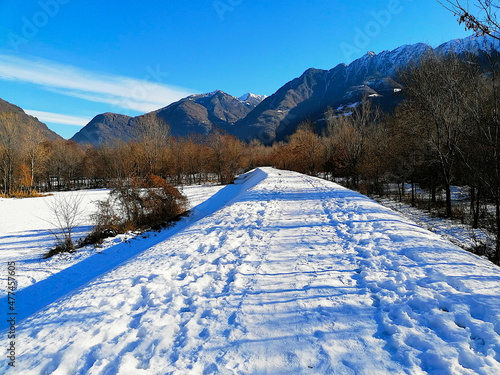 Sentiero Valellina, pista ciclabile innevata all'interno del Parco della Bosca. Strada innevata verso le Alpi che si itravedono alll' orizzonte. photo