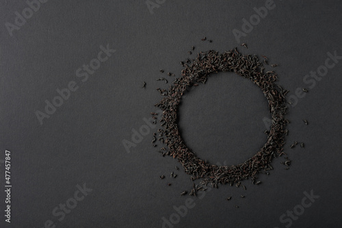 Black tea is scattered on a black background.