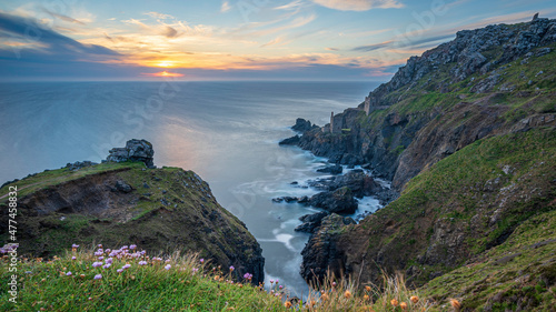 The dramatic Cornish coastline, near Lands End, with the ruins of the Botallack Tin mines, in the distance, framed against the setting sun.