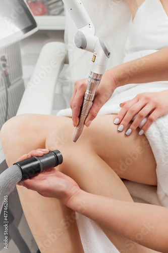 Female cosmetologist making a young woman a procedure laser hair removal for leg. Cosmetology, ionization, diamond procedures.