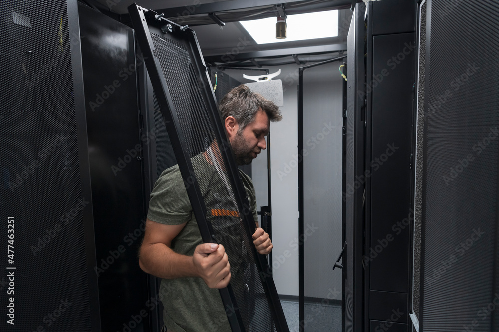 IT engineer working In the server room or data center The technician puts in a rack a new server of corporate business mainframe supercomputer or cryptocurrency mining farm. IT engineer working In the server room or data center The technician puts in a rack a new server of corporate business mainframe supercomputer or cryptocurrency mining farm.