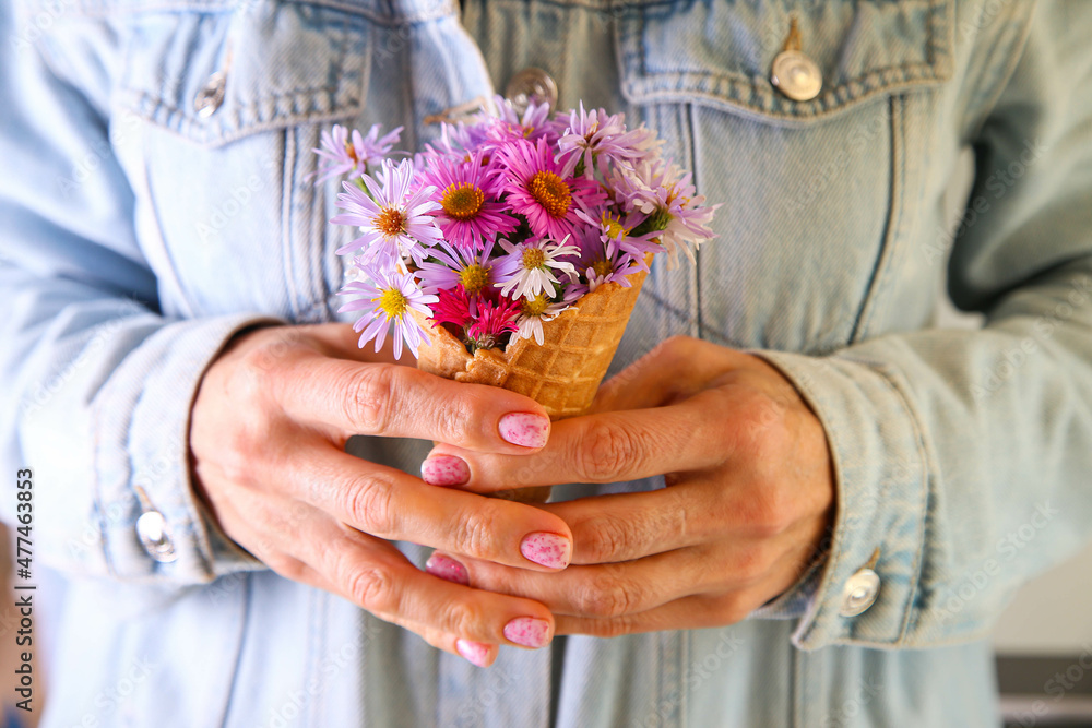 Ice cream from flowers in a waffle cup in the hands of a girl on blue background Ice cream from flowers in a waffle cup in the hands of a girl on blue background