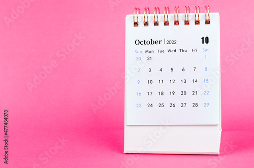 October 2022 desk calendar on pink background.