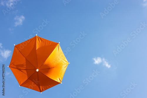 A close-up view from the low  a beautiful  translucent orange umbrella floating freely.