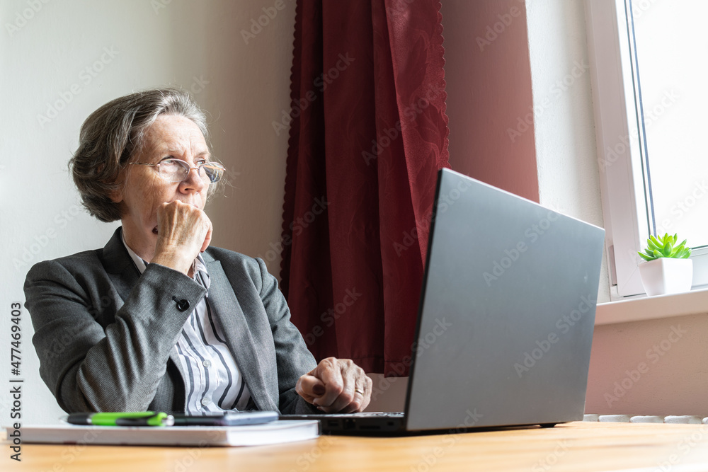 the main subject is out of focus, senior old woman female sit next at desk, home office online notebook laptop work business distance freelancer, tired bored the main subject is out of focus, senior old woman female sit next at desk, home office online notebook laptop work business distance freelancer, tired bored