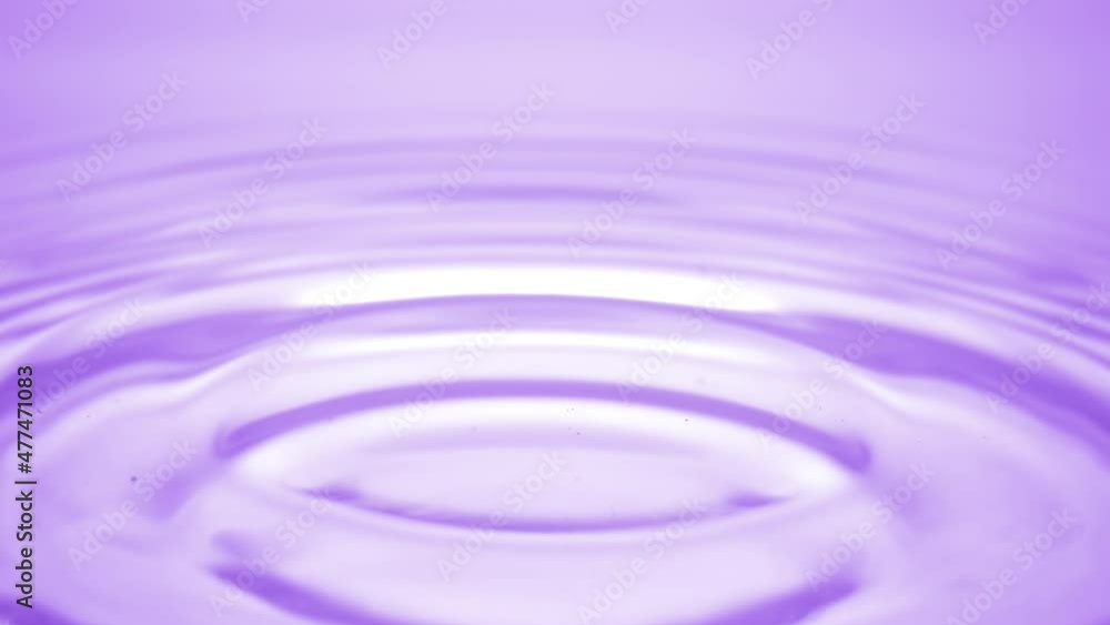 Macro shot of water drop falls down on purple transparent fluid surface creating water rings on it on purple background | Abstract skin moisturizing cosmetics formulation concept