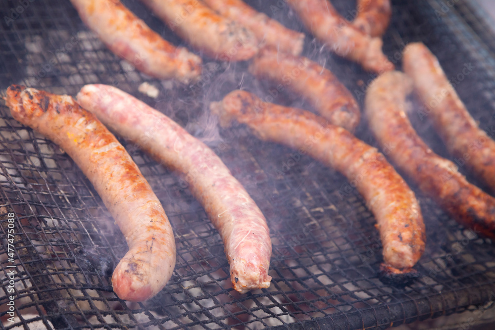 Fototapeta premium Butifarras (botifarra embutido) a la brasa o parrilla (embutido fresco) humeando (humo) al fuego