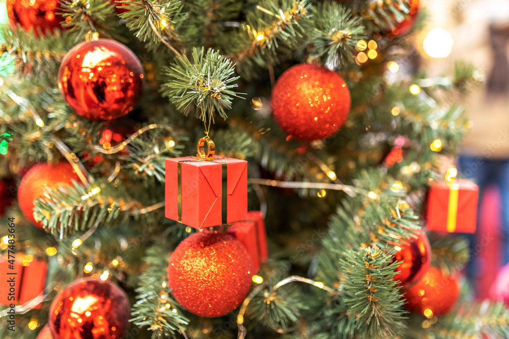 Christmas tree decorated with red ball and gift boxes. Background with bokeh. New Year