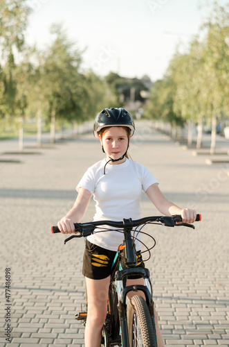 Fototapeta Naklejka Na Ścianę i Meble -  Girl 11 years old in the park with a bicycle. Children's sports and a healthy lifestyle.