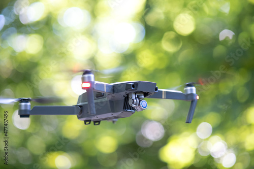 Drone aircraft with blurred fast rotating propellers and photo camera flying in air.