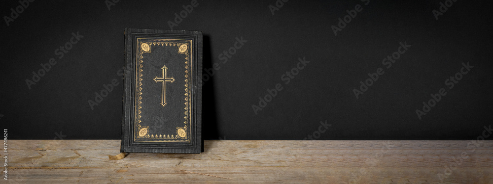 Church faith Christian background banner panorama - Old holy bible with golden cross on old rustic vintage wooden table and black wall - obrazy, fototapety, plakaty 