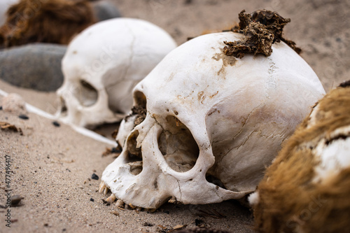 pre inca skulls on a profaned cemetery in Nasca Nazca Cahuachi. The skin and hair still on the death mans. there are ancient bones, ceramics and textile relics. 
