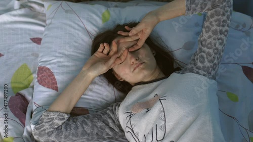 Girl wakes up in the morning in bed. The girl wakes up badly in the morning and feels tired, sleep deprived and lazy. 