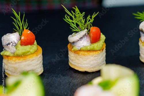 Tartlet with guacamole, anchovies, tomato, olive and dill. Special celebration meal photo