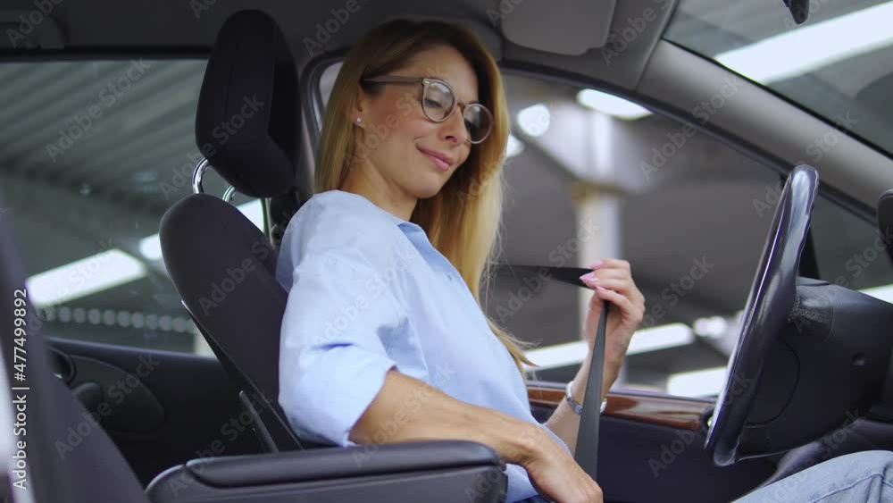 Self-confident woman fastening safety belt sitting in car, going for business Self-confident woman fastening safety belt sitting in car, going for business