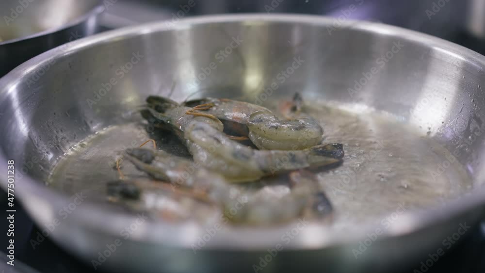 Close-up stirring raw prawns frying on pan in restaurant kitchen. Shrimps cooking on vegetable oil indoors. Delicious dinner preparation process Close-up stirring raw prawns frying on pan in restaurant kitchen. Shrimps cooking on vegetable oil indoors. Delicious dinner preparation process