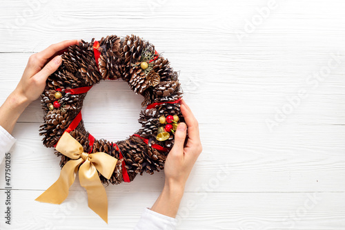 Female hands holding festive Christmas wreath. New year decoration background