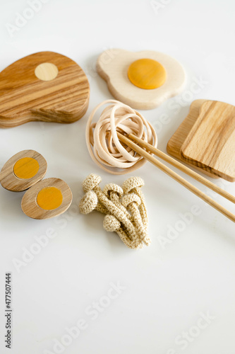 wooden toy food includes eggs, spagetti, mushrooms, steak and bread on white minimalistic backgrownd