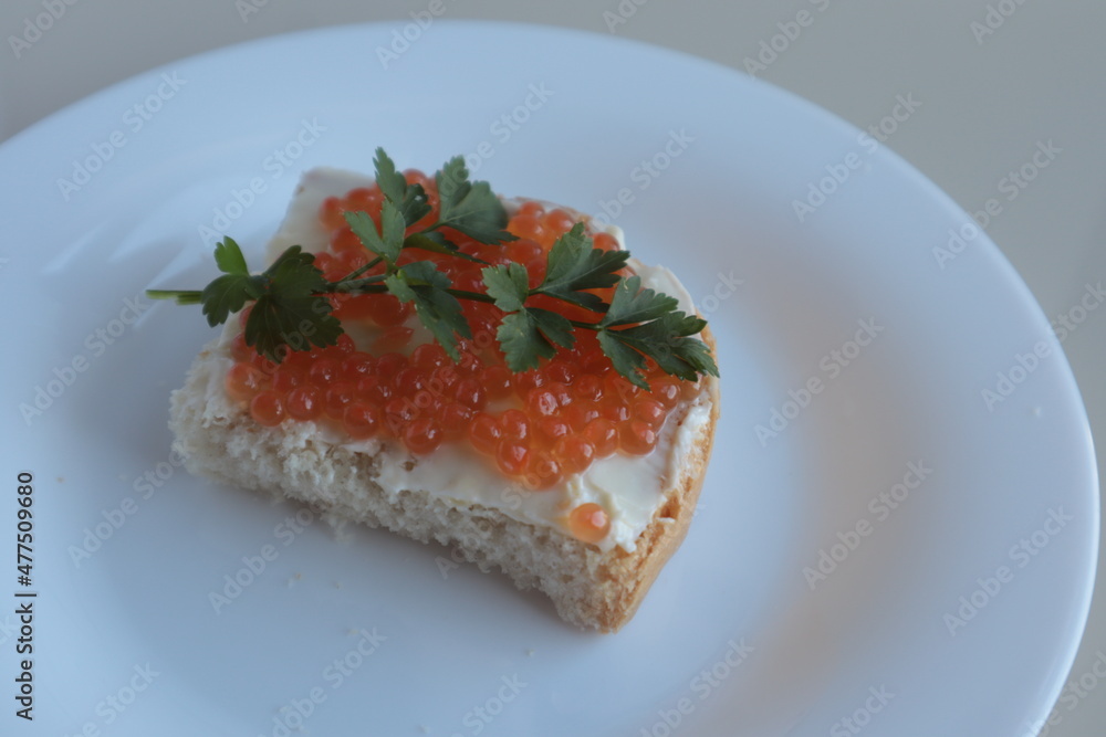 Sandwich with butter, red caviar and parsley on a white plate. Sandwich with butter, red caviar and parsley on a white plate.