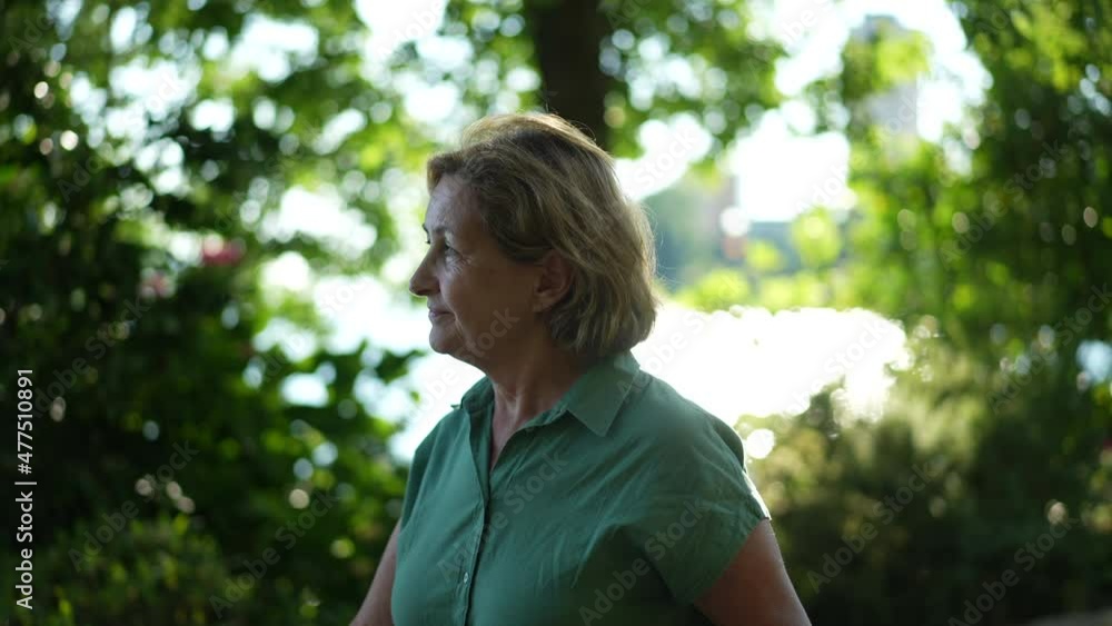 Older woman walking outdors in green urban city, senior person walks forward outside Older woman walking outdors in green urban city, senior person walks forward outside
