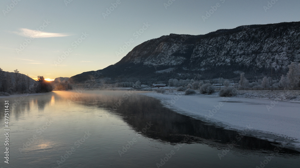 Sunrise over the river Hallingdalselva. Shot at Nesbyen, Norway. It is December and minus 20 degree outside. The water in the river is warmer than the air so therefor the smoke on the river. Frost. Sunrise over the river Hallingdalselva. Shot at Nesbyen, Norway. It is December and minus 20 degree outside. The water in the river is warmer than the air so therefor the smoke on the river. Frost.