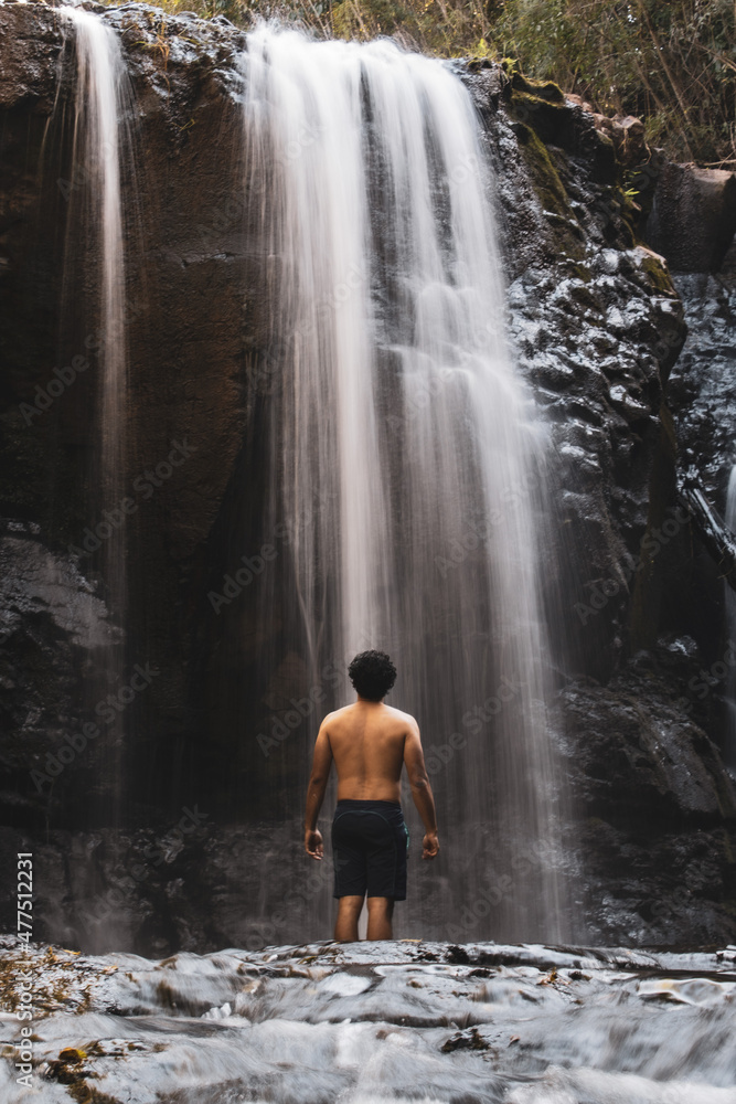 Obraz premium Cascada con hombre de espaldas
