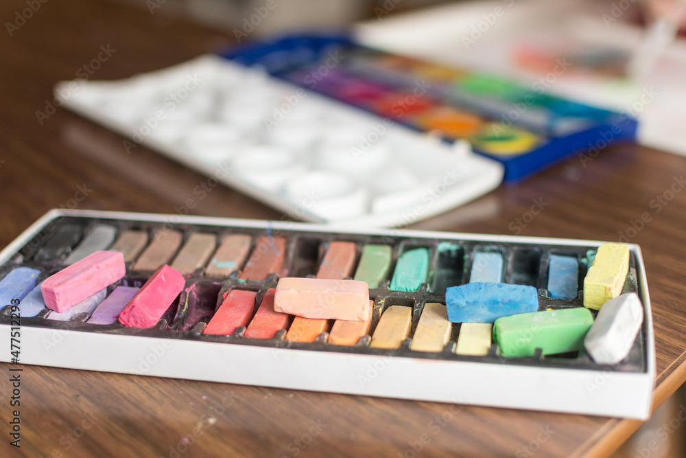 Chalk pastels and water color paints laid out in front of a high chair for child to make art with Chalk pastels and water color paints laid out in front of a high chair for child to make art with