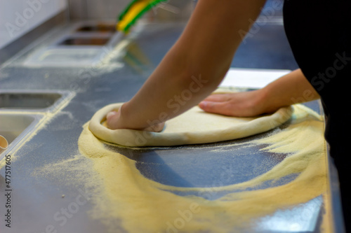 rolling out pizza bases from dough with pizza hands in a restaurant close-up
