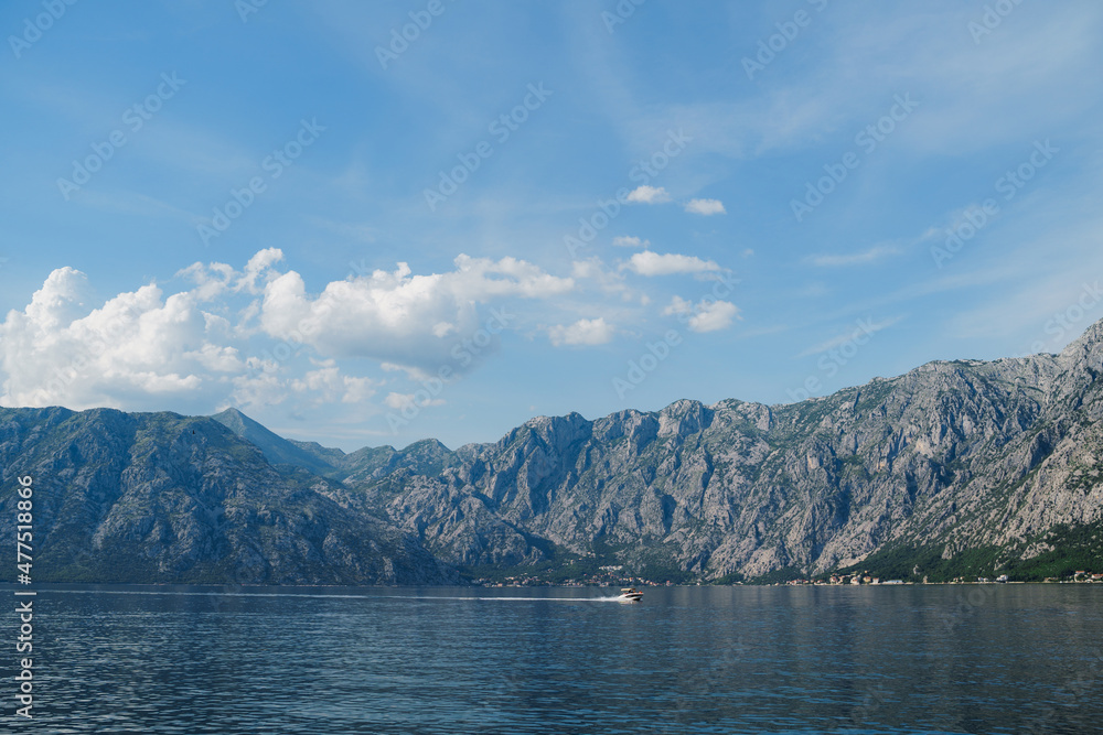Motor boat sails along the Bay of Kotor leaving a white foamy trail