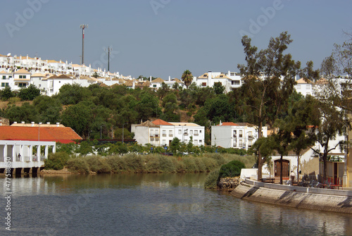 River Gilao with a hill, trees and residential buildings in background in Tavira
