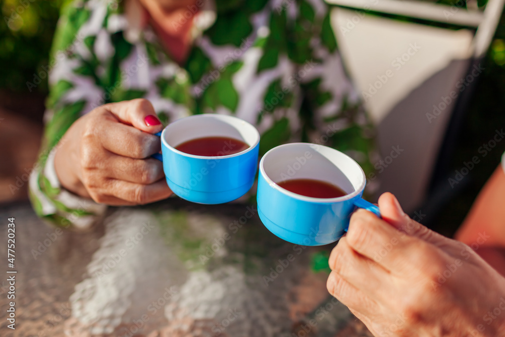 Senior family couple drinking tea in cafe. People enjoying beverages outdoors. Close-up of cups Senior family couple drinking tea in cafe. People enjoying beverages outdoors. Close-up of cups