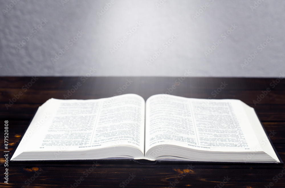 Open Bible book, on a wooden table. Desk lamp. Light from a book Open Bible book, on a wooden table. Desk lamp. Light from a book