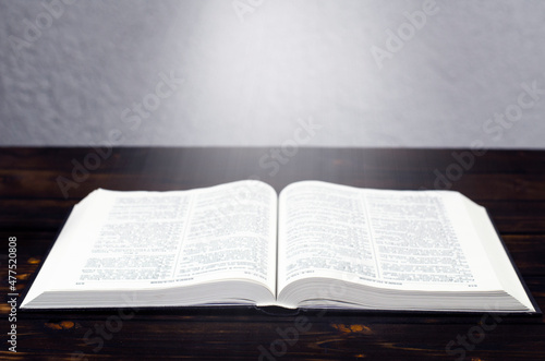Foto Open Bible book, on a wooden table. Desk lamp. Light from a book