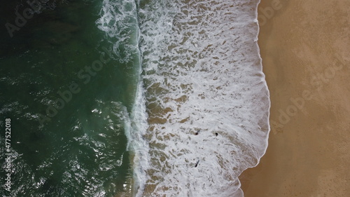 Ocean waves and sandy beach on sunny day. Aerial view