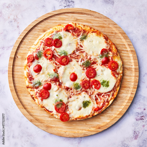 Single caprese italian pizza on wooden plate on marble surface