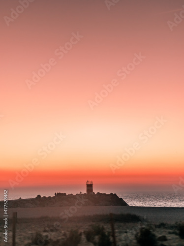Scenic Lighthouse And Pink Sky Sunset At The Beach In Nazareth Portugal