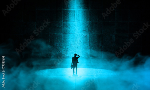 Businessman standing on Spotlight in Concrete dark Room with fogs effect. Man thinking in solution to get-out. Difficulty and Business Solutions Concept 