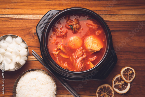 Kimchi soup in hot iron pot with rice and Kimchi pickle on wooden table, Korean traditional Kimchi soup with Tofu mushroom hot pot.